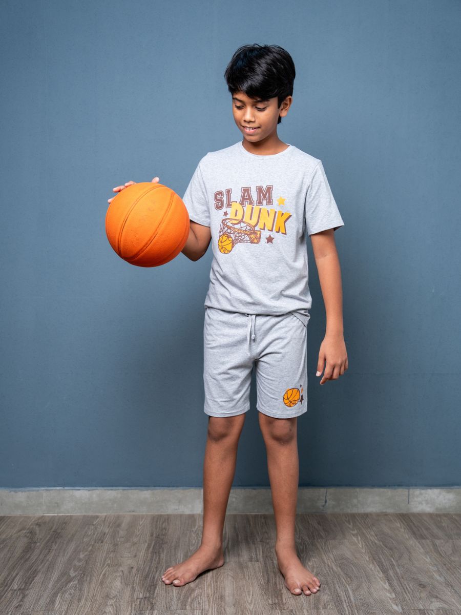 Child holding an orange basketball wearing a ‘Slam Dunk’ t-shirt against a blue wall.
