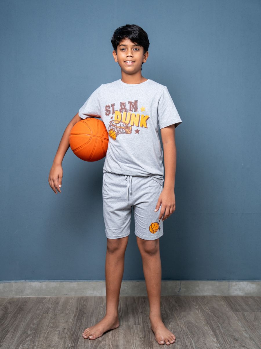 Child holding a basketball wearing a ‘Slam Dunk’ t-shirt against a blue wall.