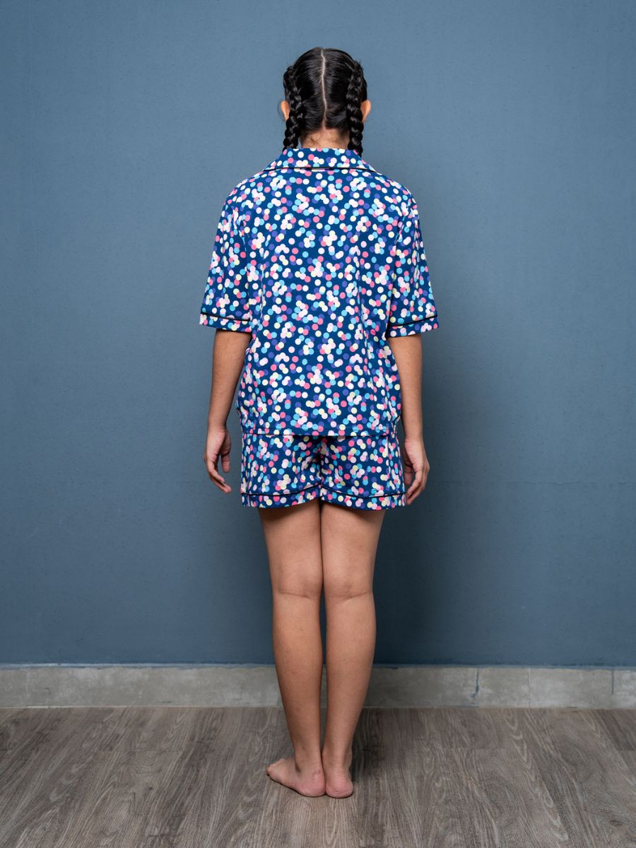 Person wearing a blue floral pajama set against a gray wall.