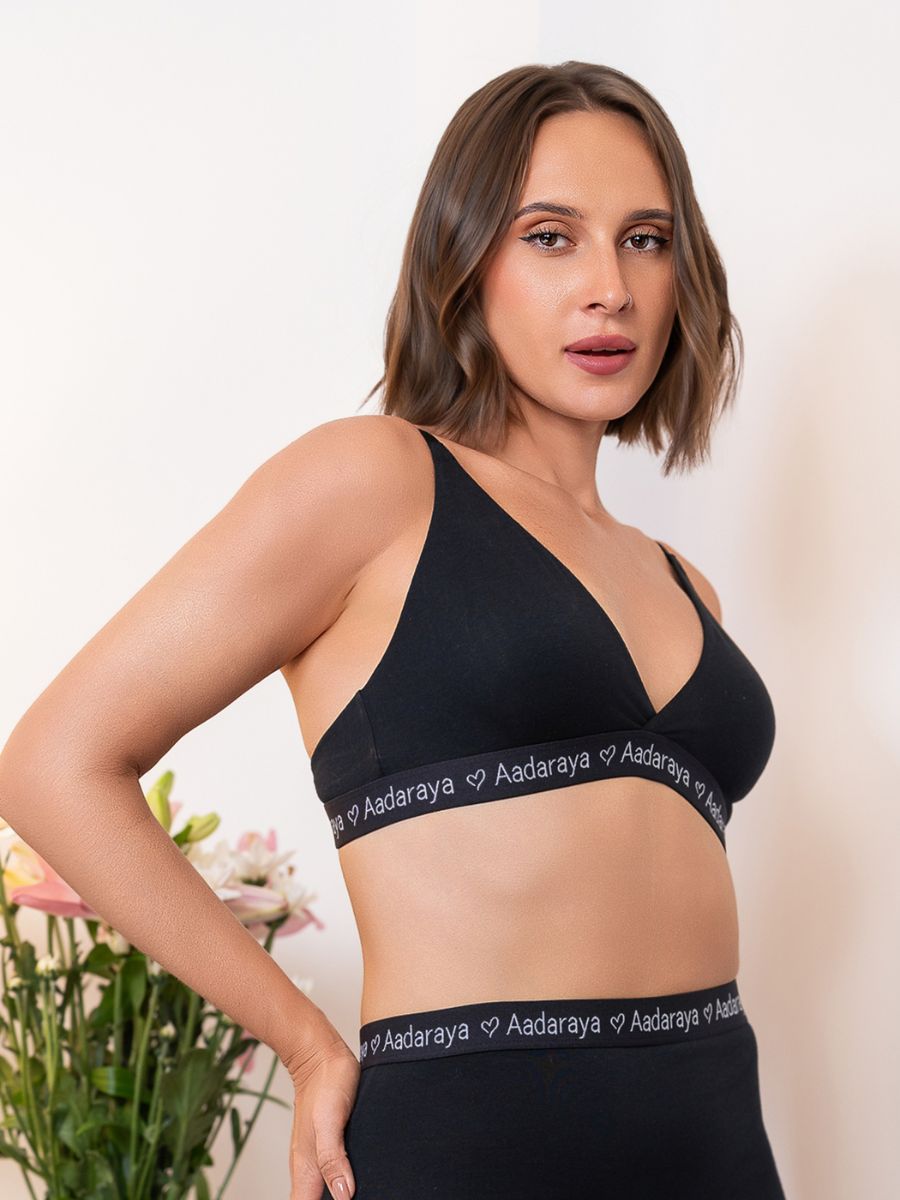 Woman wearing a black sports bra and leggings with ‘Aadaraya’ branding on a neutral background