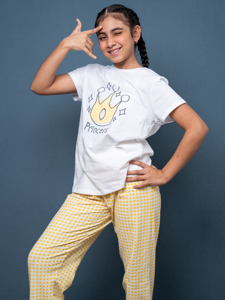 Girl wearing a white t-shirt with a graphic design and yellow checkered pants on a blue background