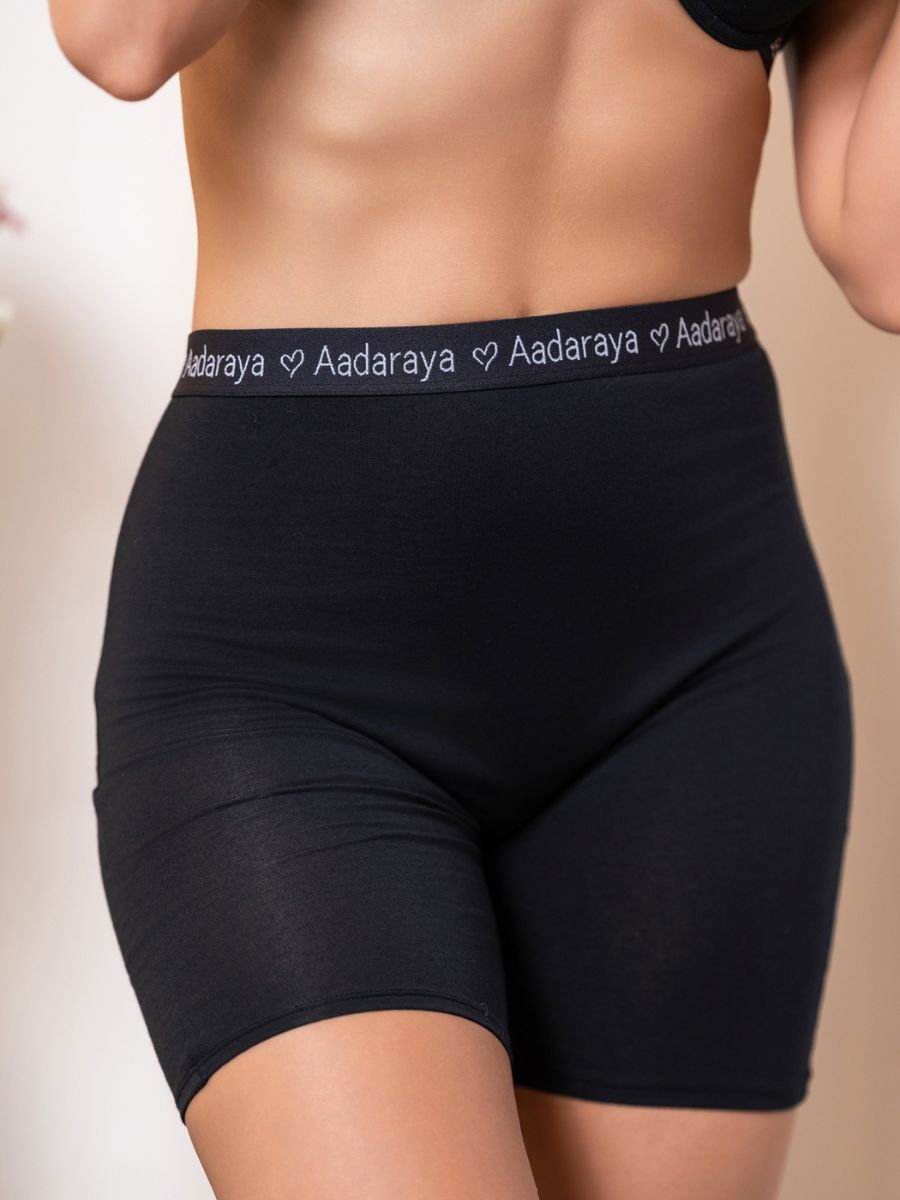 Black shorts with ‘Aadaraya’ waistband on a neutral background