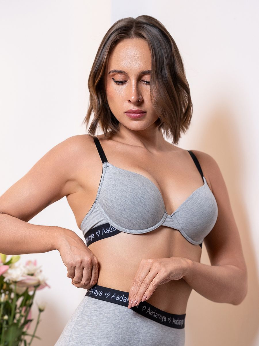 Woman wearing a gray bra with visible branding against a neutral background