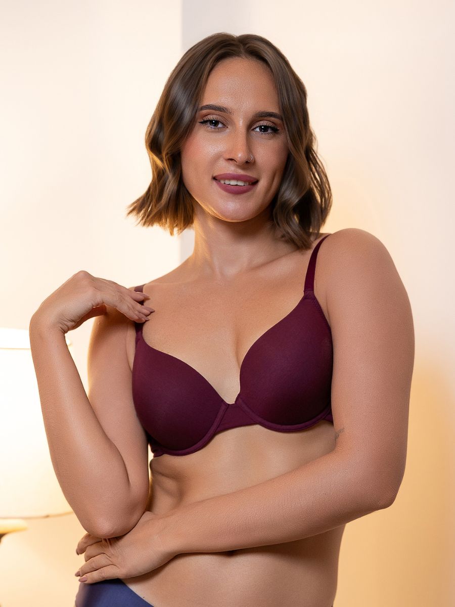 Woman wearing a burgundy bra against a neutral background