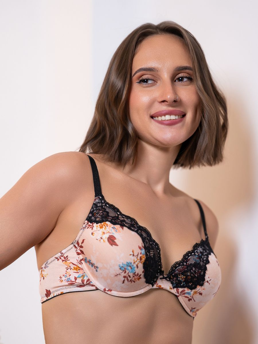 Woman wearing a floral bra with lace trim against a plain background