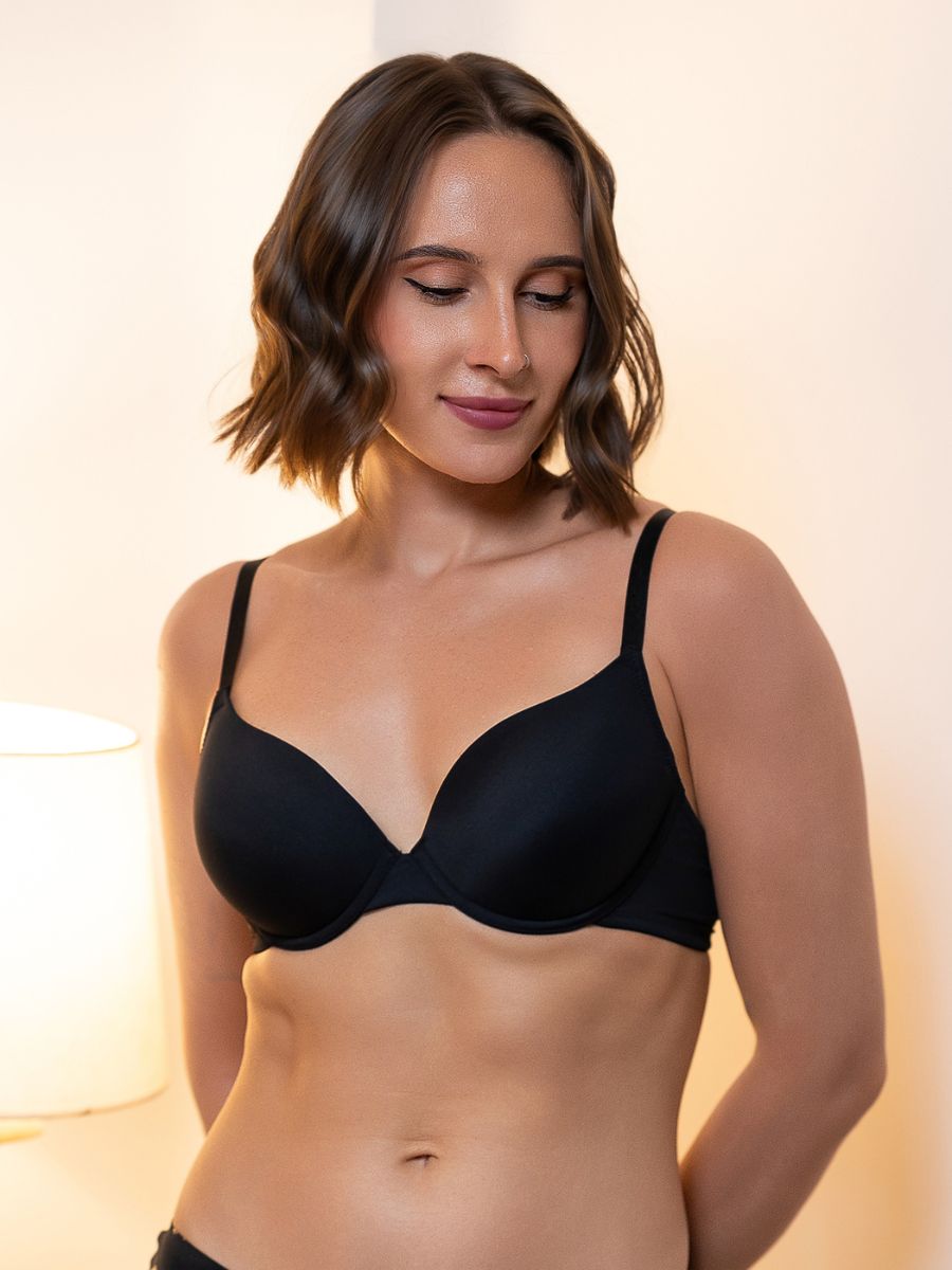Woman wearing a black bra against a neutral background