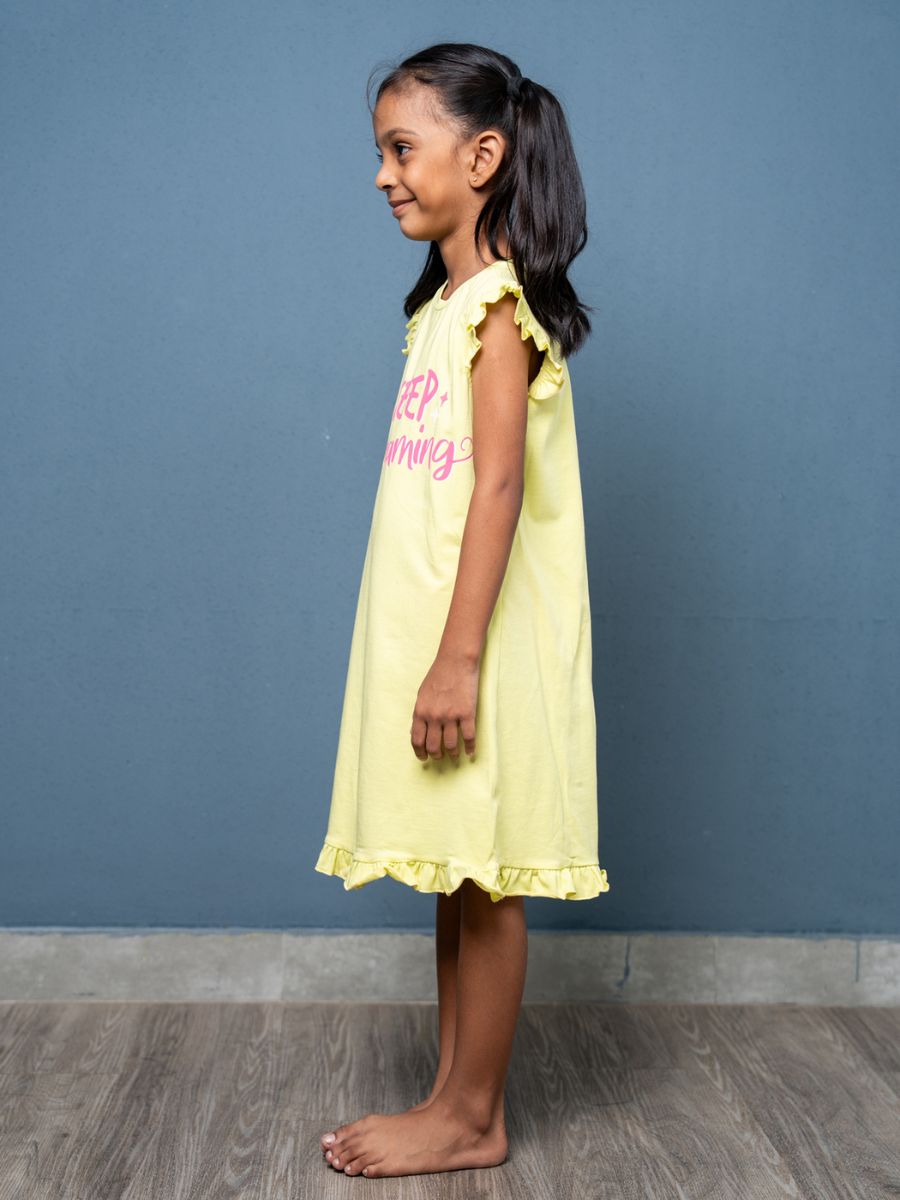 Young girl wearing a yellow dress with text against a blue wall