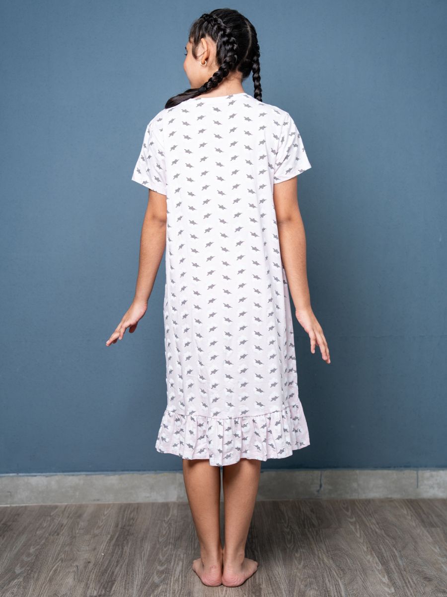 Girl wearing a white dress with a subtle pattern against a blue wall.