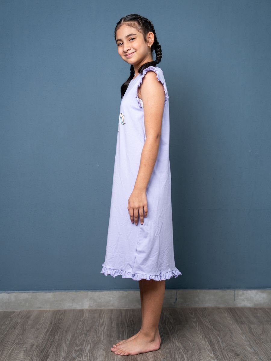 Young girl wearing a light purple dress against a blue wall