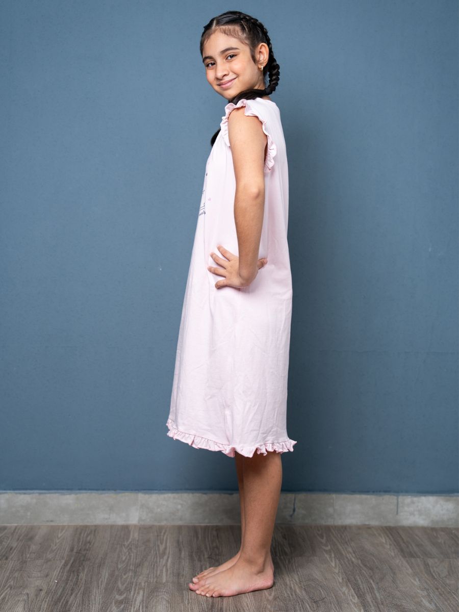 Young girl wearing a lilac nightgown against a blue wall.