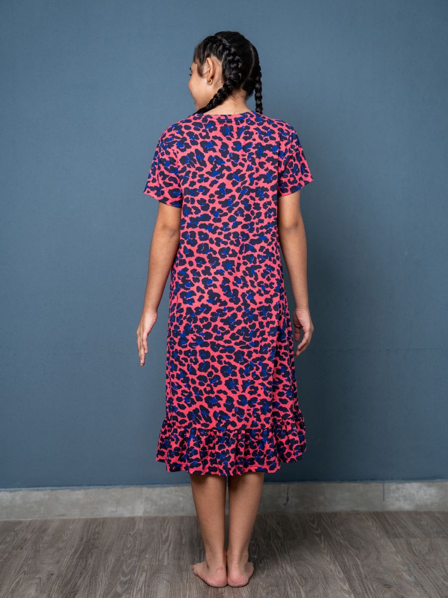 Person wearing a pink and blue patterned dress against a blue wall.