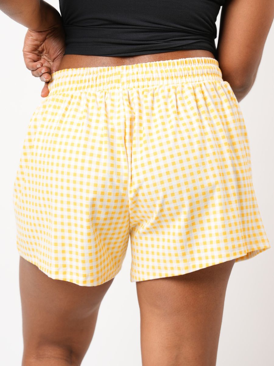 Yellow checkered shorts worn by a person on a white background